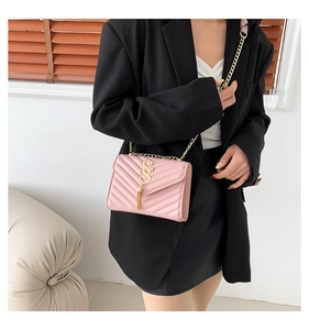 Detailed view of pink quilted handbag with gold logo, tassels, and chain shoulder strap