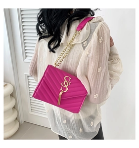Détail du sac bandoulière matelassé rose avec logo doré et pompon sur modèle