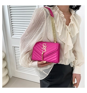 Detailed macro view of hot pink quilted bag with golden S logo and fringe chain strap