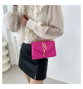Detail of fuchsia chevron quilted bag featuring gold metal fringe and chain strap