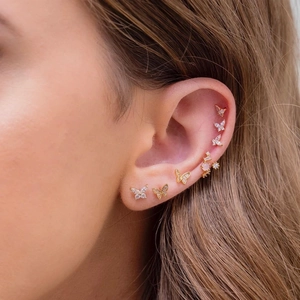 Close-up of 18K gold plated butterfly stud earrings set with pink stones on the ear