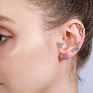 Elegant silver butterfly earrings set with sparkling zircons worn on model's ear