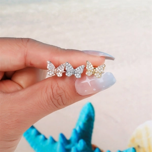 Detailed view of three butterfly stud earrings in gold, silver, and rose gold finishes