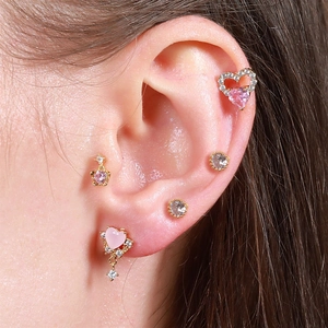 Close-up of pink heart stud earrings and gold ear cuffs set for multiple piercings