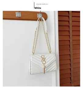 Detail of white PU leather crossbody bag with V-quilt stitching and gold tassel logo