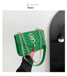 Detail of green quilted bag with V-shaped texture, gold S-buckle and chain strap