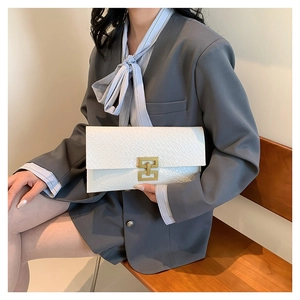 Clutch bianca in pelle goffrata coccodrillo con chiusura dorata e giacca grigia