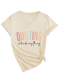Detail of V-neck apricot tee with rolled sleeves and knot design featuring quilting slogan