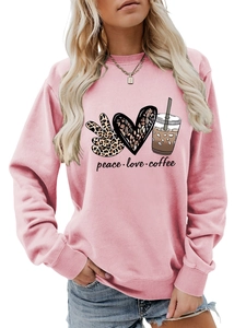 Close-up of peace love coffee graphic on pink long sleeve crewneck sweatshirt