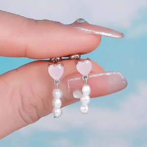 Detail of pink heart-shaped crystal earrings with triple vertical pearls on silver studs
