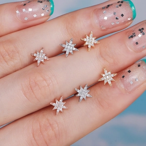 Close-up of starburst stud earrings in gold, silver, and rose gold with zircon stones