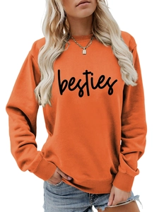 Close-up of the black hand-lettered besties print on an orange crewneck sweatshirt