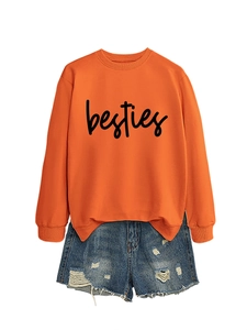 Detail of orange crewneck besties sweatshirt paired with distressed denim shorts