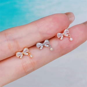 Three zircon bow ear cuffs in gold, silver, and rose gold with dangling crystal charms