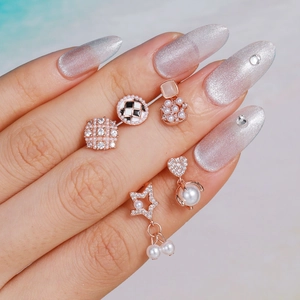 Roségouden schaakbord oorknopjes set met strass en parels op een hand van model