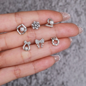 Bowknot and pearl stud earring set in silver stainless steel shown on fingertips