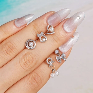 Elegant silver bow and pearl earrings set with zircon accents on a finger model