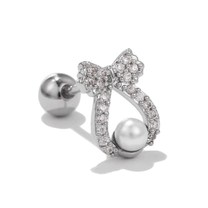 Detailed macro shot of silver bow stud earring with micro-pave stones and white pearl