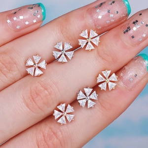 Sparkling zircon snowflake ear studs in gold and silver finishes held by hand