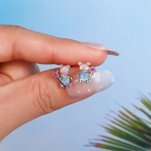 Macro shot of silver bear studs with opal stones and star wand on a fingertip