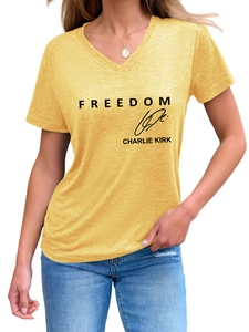 Detail of yellow V-neck tee featuring black FREEDOM text and Charlie Kirk signature