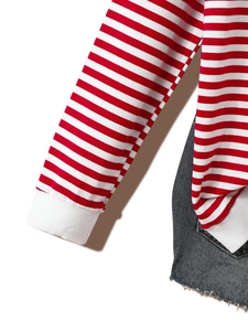 Detail of red and white striped long sleeve top with ribbed cuffs and washed denim jeans