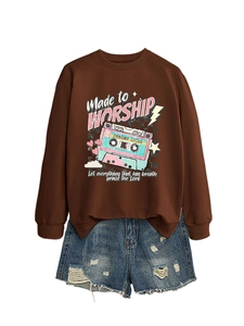 Flat lay of brown 'Made to Worship' sweatshirt paired with distressed blue denim shorts