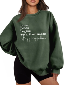 Detail of a green oversized sweatshirt featuring a bold white slogan print on the front
