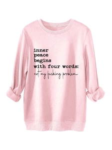Detail of pink crewneck sweatshirt featuring black inner peace begins with printed slogan