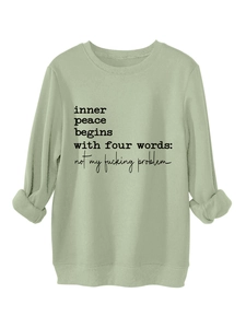 Detail of sage green sweatshirt cuffs and fabric with 'inner peace' printed slogan
