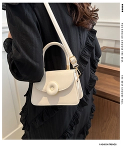 On-body shot of cream faux leather crossbody bag with circular buckle and gold hardware