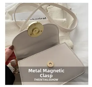 Detailed close-up of the golden magnetic buckle on the cream leather handbag