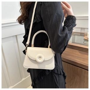 Close-up of minimalist ivory leather crossbody bag with round magnetic buckle details