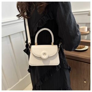 Beige mini crossbody bag with donut ring lock and gold hardware on a female model