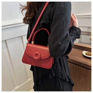 Detail of red leather crossbody bag featuring a donut-shaped ring buckle and smooth finish