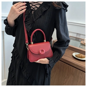 Detail of red square crossbody bag featuring a unique matte ring buckle and gold hardware