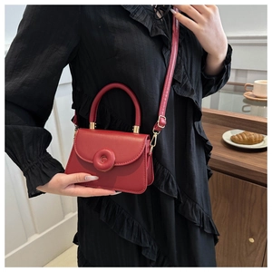 Red leather mini satchel handbag with unique donut buckle shown in a lifestyle setting