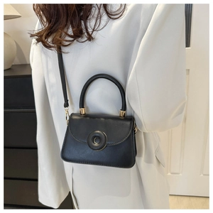 Close-up of classic black crossbody bag with donut ring clasp on a model's shoulder