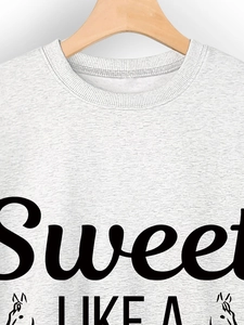 Close-up of crewneck sweatshirt ribbing and Sweet Like A graphic print on grey fabric
