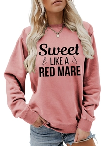 Close-up of pink crewneck sweatshirt featuring artistic horse graphics and black lettering