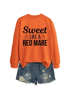 Flat lay of an orange crewneck sweatshirt with graphic print and ripped denim shorts