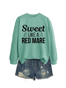 Close-up of mint green crewneck sweatshirt with black graphic print and denim shorts