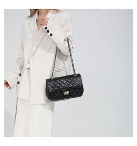 Close-up of black quilted crossbody bag with gold chain strap and metal turn-lock