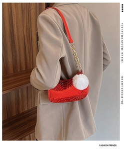 Detail of red patent leather baguette bag with crocodile texture and white fluffy charm