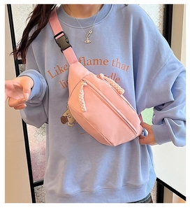 Detailed shot of pink nylon chest bag with adjustable strap and decorative woven zipper pull