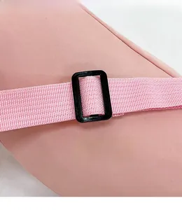 Detailed macro view of pink nylon chest bag with adjustable woven shoulder strap