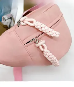 Detailed close-up of pink nylon chest bag with metallic zipper and woven cord puller
