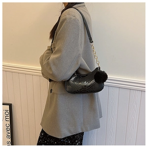 Detail of black faux leather underarm bag with crocodile texture and gold chain strap