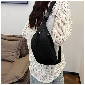 Black nylon crossbody waist bag with adjustable strap worn by a model in casual setting