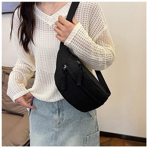 Detail of black nylon crescent chest bag featuring woven zipper pulls and wide strap